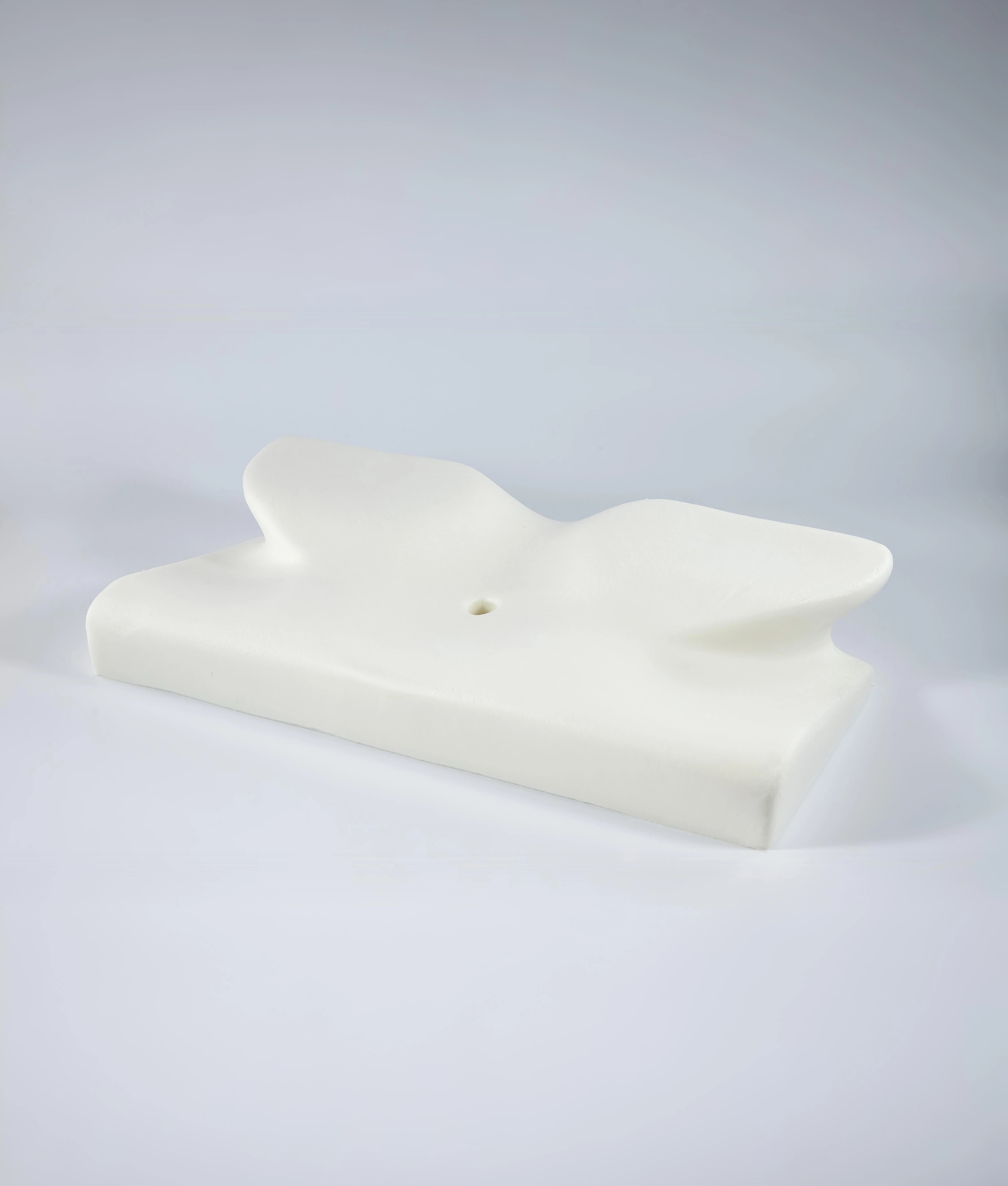 The CozyRest pillow's bare white memory foam core without its cover, showing the butterfly-shaped contour and the small center hole
